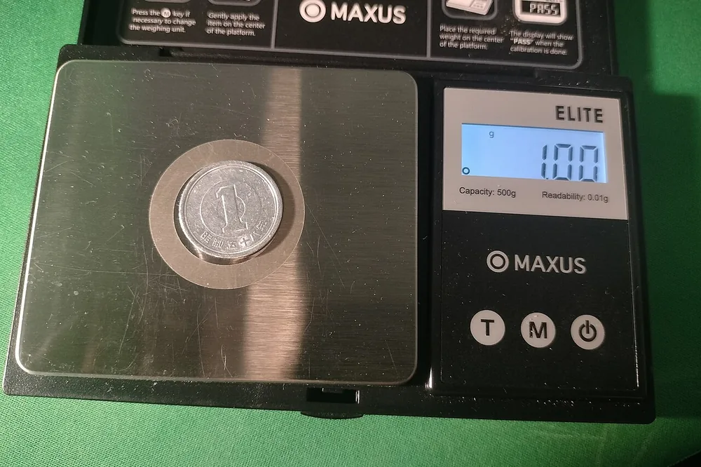 はかりにのせた1円玉。表示は1グラム